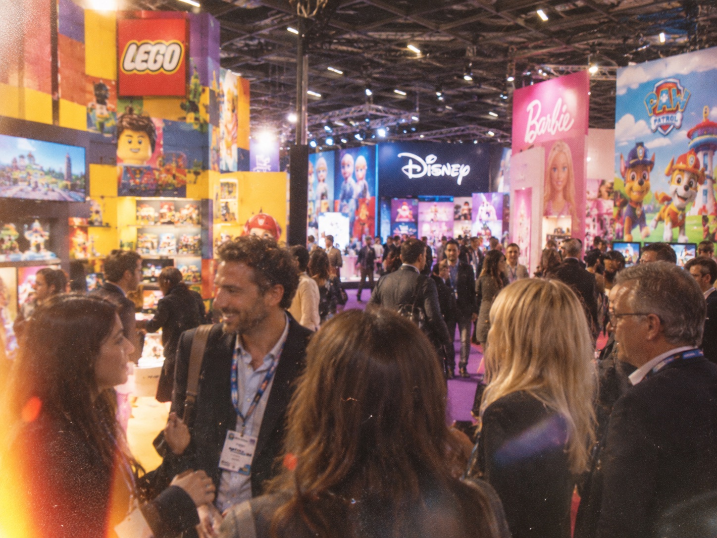 Visitors crowding a toy and licensing fair under the stands of LEGO, Disney, Barbie and Paw Patrol